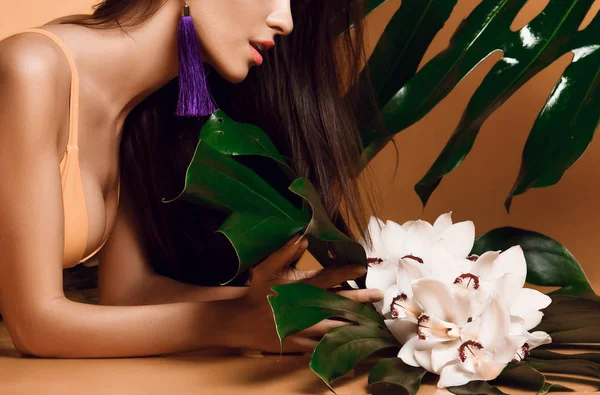 Молодая красивая сексуальная женщина с идеальной гладкой кожей провести тропические листья и цветы орхидеи — стоковое фото