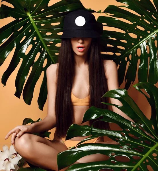 Mladá krásná sexy žena s perfektní hladkou pletí držet tropické listy v letním klobouku čepice — Stock fotografie