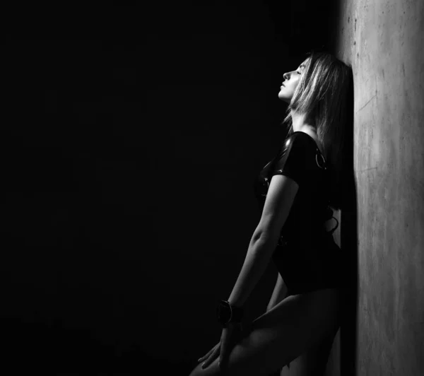 Mladá krásná sexy brunetka v černé moderní kožený hadr pózný v tmavé místnosti — Stock fotografie