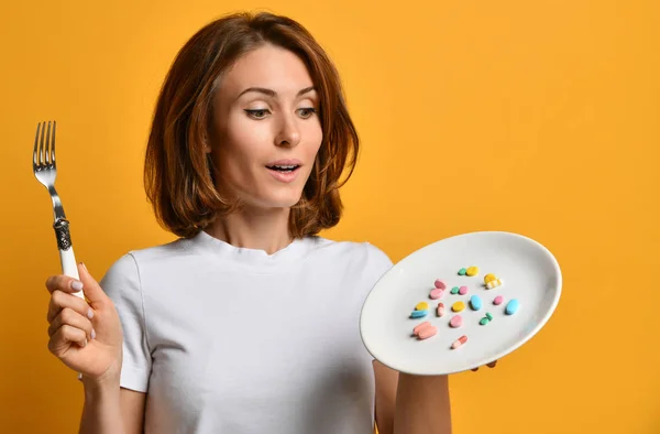 Woman nutritionist hold a white plate with different color tablet pills diet supplements prescription weight loss drugs on yellow — Stock Photo, Image