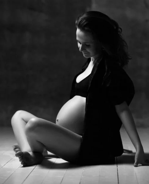 Красивая молодая беременная счастливая мать женщина позирует на темном фоне — стоковое фото