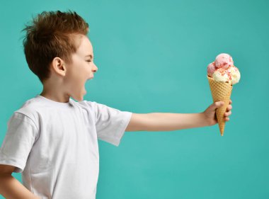 Bebek çocuk mavi nane arka plan üzerinde waffle koni çilek ve vanilyalı dondurma üç kepçe tutun