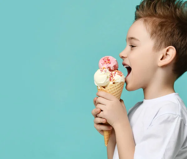 Niño niño sostiene tres cucharadas de helado de fresa y vainilla en gofres cono sobre fondo de menta azul —  Fotos de Stock