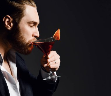 Zevk gözleri kapalı moda takım elbise sakallı barmen Brutal modern adam martini cam turuncu ile lezzetli bir kırmızı kokteyl içecekler