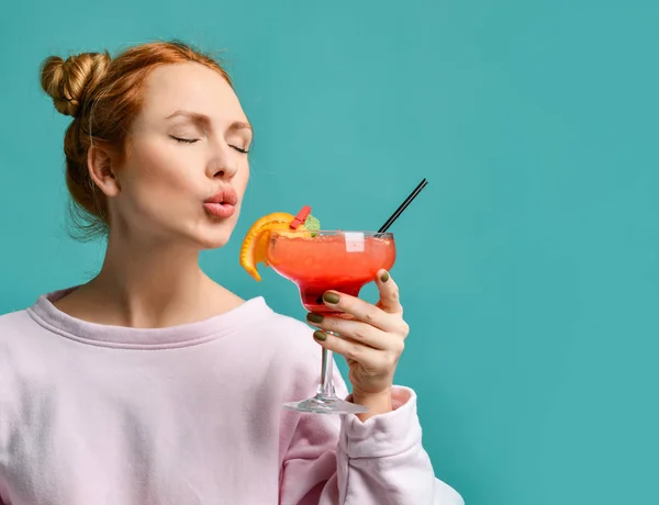 Giovane donna bionda con i capelli in panino e gli occhi chiusi andando a provare un cocktail alla fragola margarita — Foto Stock