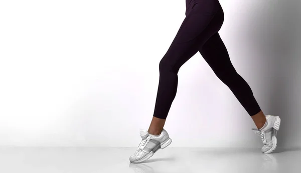 Mulheres esportivas pernas andando no esporte desgaste em um branco — Fotografia de Stock