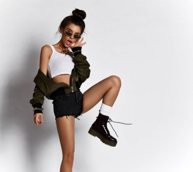 Young beautiful hipster girl sitting posing full body in little sexy dress brown spring jacket and modern stylish boots 