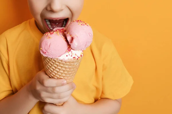 Menino bebê garoto comendo sorvete de morango em waffles cone feliz gritando rindo no fundo amarelo — Fotografia de Stock