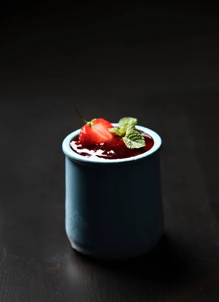 黒い背景に青い瓶に新鮮な熟した自家製ヨーグルトパナコッタのイチゴとミントの砂漠 — ストック写真