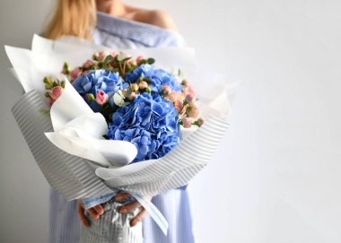 Kadın elleri beyaz mavi ortanca çiçek ve pembe gül bukettutun 