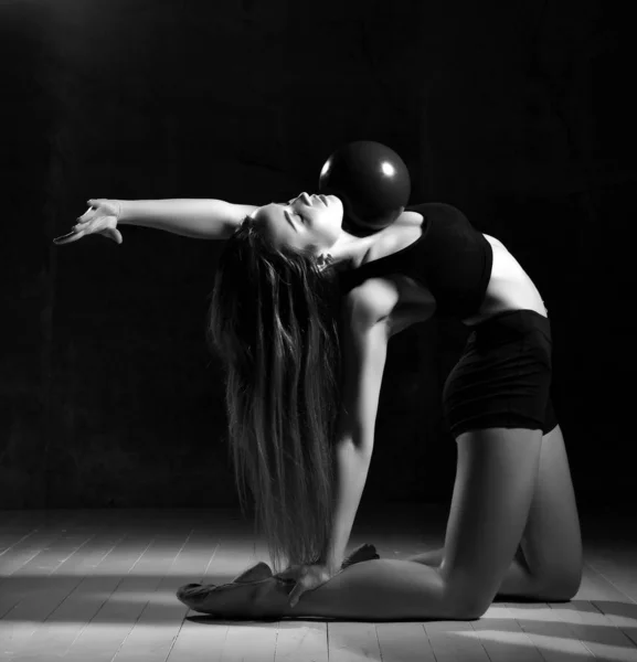 スポーツクラブでボールでフィットネスエクササイズをストレッチ体操をしている若いスポーティな女性 — ストック写真