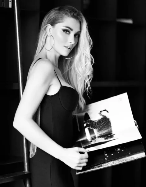 Joven bonita mujer en sexy vestido negro poco lectura revista o libro en habitación moderna — Foto de Stock
