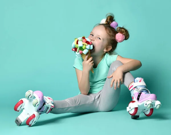 Дівчинка в роликових ковзанах сидить на підлозі у вільному текстовому просторі копіювання тримає великий і смачний морозиво у вафельному конусі — стокове фото