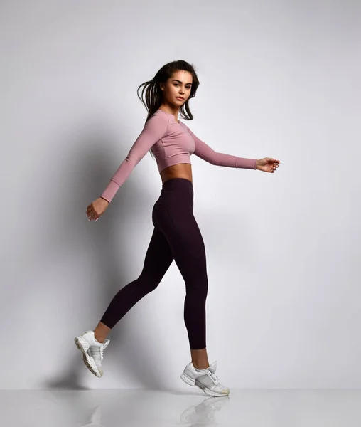 Jovem atlético mulher morena menina em uma boa forma na moda sportswear andando no ginásio uniforme faz exercícios de cardio — Fotografia de Stock