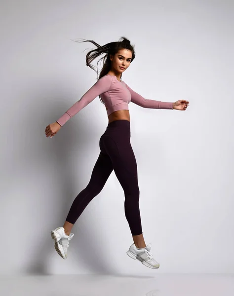 Jovem atlético mulher morena menina em uma boa forma na moda sportswear andando no ginásio uniforme faz exercícios de cardio — Fotografia de Stock