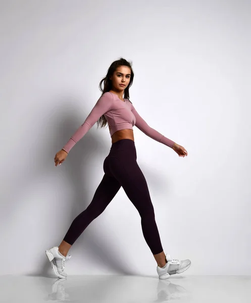 Young athletic woman brunette girl in a good shape in trendy sportswear walking in gym uniform does cardio exercises — Stock Photo, Image