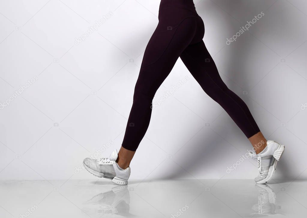 Young athletic woman brunette girl in a good shape in trendy sportswear walking in gym uniform does cardio exercises 