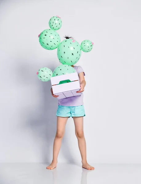 Young asian girl hide face behind cactus balloon in pastel pink and purple flower box made of green round balloons