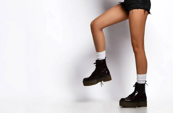 Vackra kvinnliga ben bär läder svarta stövlar i jeans designers shorts och mörkgrön kvinna jacka Walking hoppning — Stockfoto