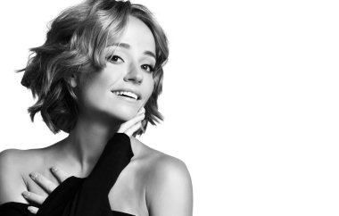 Kıvırcık saçlı güzel kadın oyuncu siyah elbiseli mutlu yüz duyguları gülümseyerek poz. Siyah beyaz 