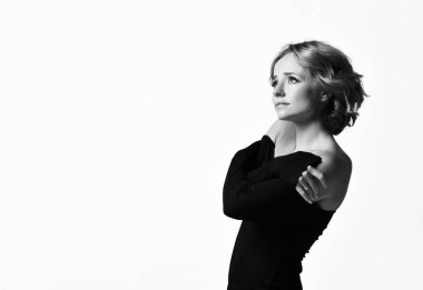 Kıvırcık saçlı güzel kadın oyuncu siyah elbiseli mutlu yüz duyguları gülümseyerek poz. Siyah beyaz 