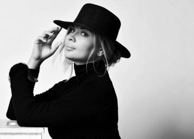 Siyah beyaz portre sarışın kadın romantik kız siyah şapkalı ağzına kadar kenarlı ve boğazlı yakalı beyaz bize bakıyor