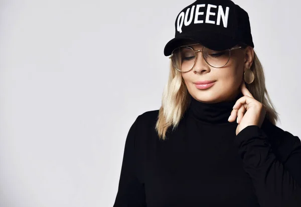 Портрет блондинки в модній чорній шапці, светр і великі окуляри тримають її палець на її вухо — стокове фото