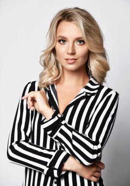 Resmi giyim çizgili bluz genç zarif iş kadını dudaklarında bir ışık sırıtış ile kamera bakıyor