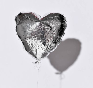 Parti gölge ile beyaz gri arka plan üzerinde sönmüş gümüş kalp balon nesne üzerinde