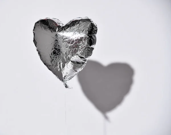 Partito è sopra sgonfiato argento cuore palloncino oggetto su sfondo grigio bianco con ombra — Foto Stock