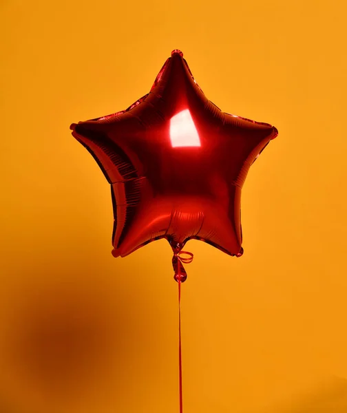 Single big red star balloon ballon object for birthday party on yellow — Stock Photo, Image