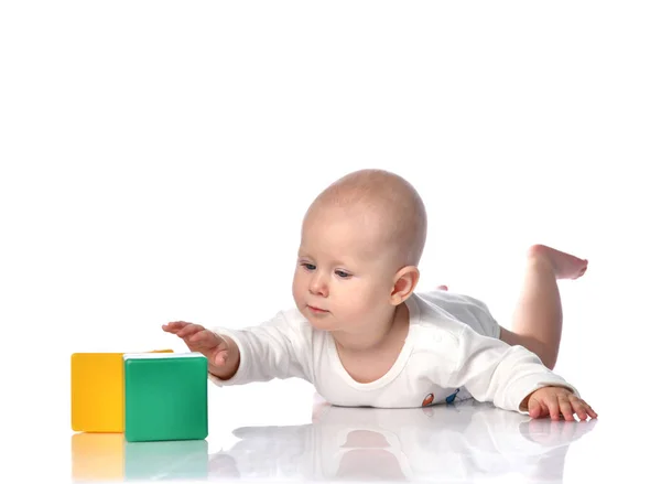 Bambino neonato bambino sdraiato e giocare con i giocattoli di mattoni gialli verdi isolati su un bianco — Foto Stock
