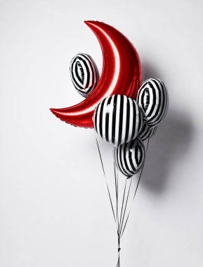 Bir grup büyük siyah beyaz çizgili balon ve doğum günü partisi için kırmızı ay metalik balonu.