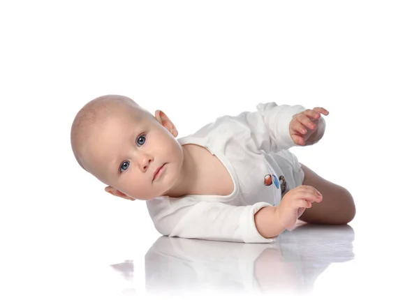 Infant child baby boy toddler in white bodysuit is lying on its side, trying to roll over on white — Stock Photo, Image