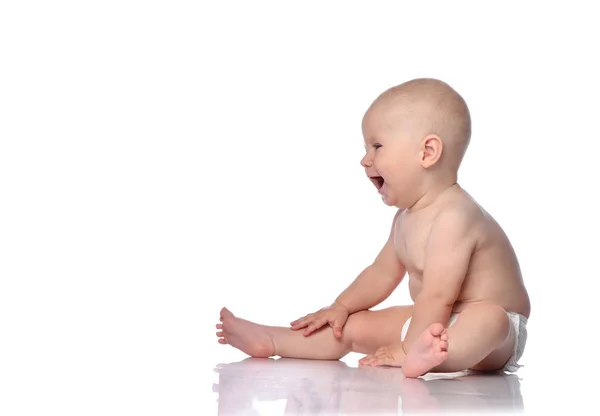 Bebé bebé en pañal sentado mirando algo delante de él en el espacio de copia y risas felices en blanco —  Fotos de Stock