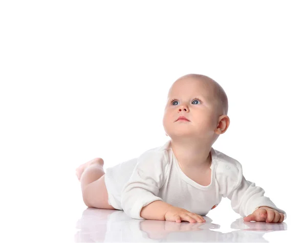 Infant child baby boy toddler in white shirt lying on his stomach looking up, quiet, interested in something on white — Stock Photo, Image