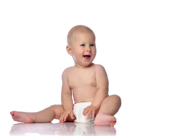 Happy infant child baby boy toddler in diaper is sitting  looking at something near him on copy space on white — Stockfoto