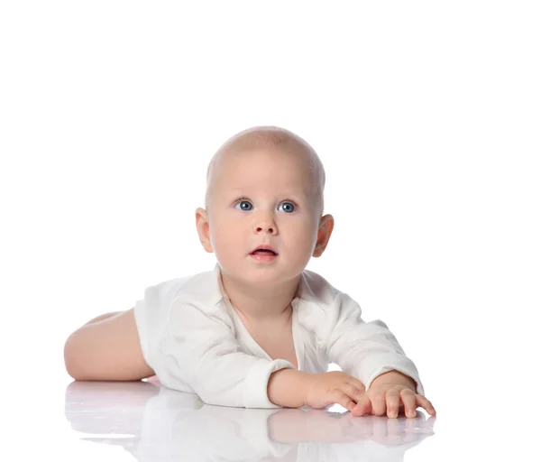 Criança infantil bebê criança de camisa branca deitado em seu estômago olhando para cima, quieto, sua atenção é capturada por algo — Fotografia de Stock