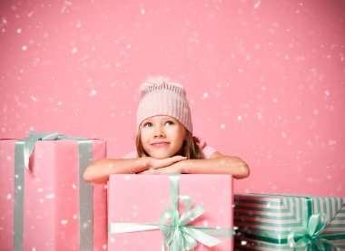 Şirin kız hediye kutularının başında oturmuş kar altında ne olduğunu tahmin etmeye çalışıyor.