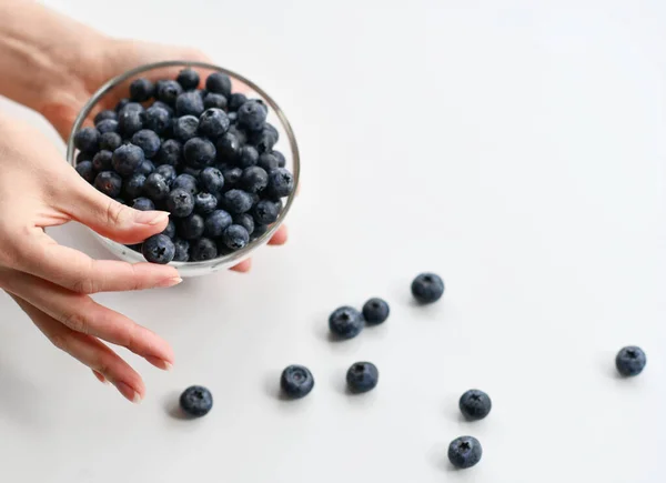 Vrouw demonstreert bosbessen met volle kom met de andere hand. Biologisch superfood concept voor gezond eten — Stockfoto