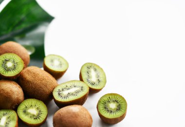 Fotokopi alanı olan tropikal yaprak arka planında tam ve yarıya indirilmiş kivi. Sağlıklı yemek için organik süper gıda kavramı