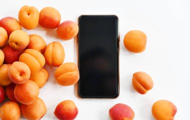 Kayısılar akıllı telefon arkaplanında fotokopi alanı ile dağılmış durumda. Sağlıklı yemek için organik süper gıda kavramı 