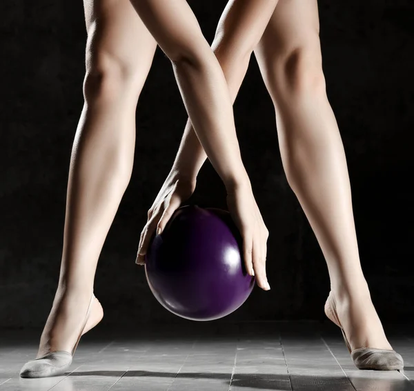 Ρυθμική γυμναστική έννοια. Αθλητική γυναίκα χέρια και πόδια closeup σύνθεση τεντώνοντας ασκήσεις φυσικής κατάστασης προπόνηση με μωβ μπάλα — Φωτογραφία Αρχείου