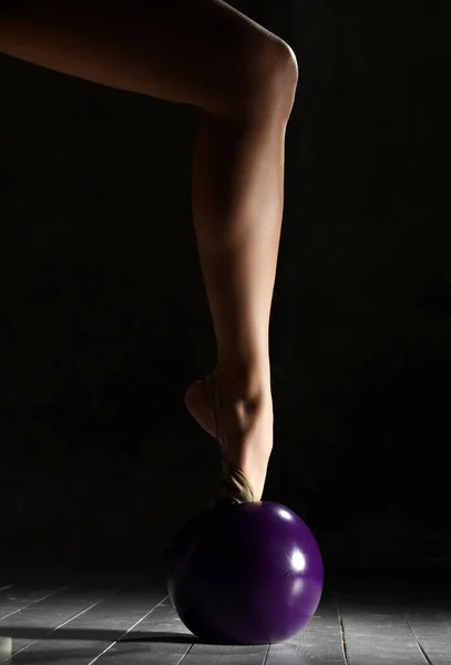 Концепция художественной гимнастики. Спортивная женщина руки и ноги крупным планом композиция растяжения фитнес упражнения с фиолетовым мячом — стоковое фото
