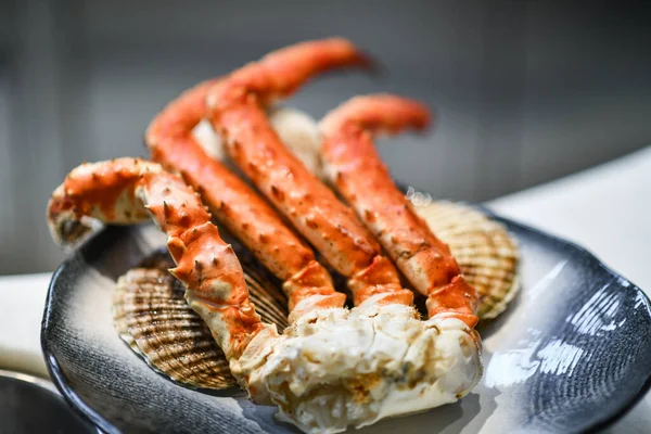 Närbild av stora färska välsmakande krabba ben dekorerade med havet pilgrimsmussla skal — Stockfoto