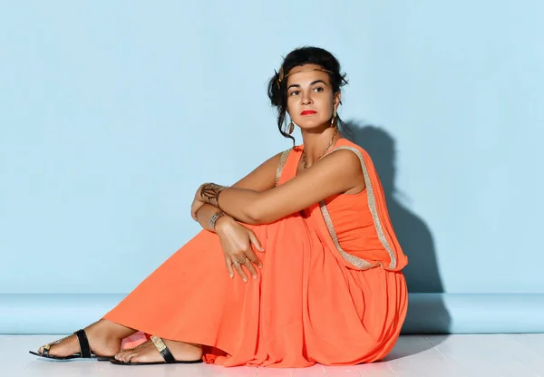 Pensive attraktive Frau mit griechischem Aussehen trägt Schmuck mit traditioneller ethnischer Dekoration auf dem Boden sitzend Studioaufnahme — Stockfoto