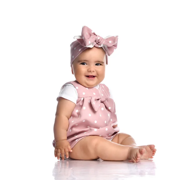 Cute smiling infant baby girl toddler in polka-dot dress and headband with bow sits on the white floor — Stock Photo, Image