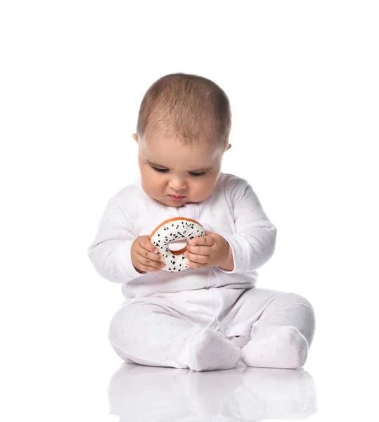 总体上看，专注于幼儿的白衣幼儿坐在手上拿着甜甜圈玩具的地板上 — 图库照片