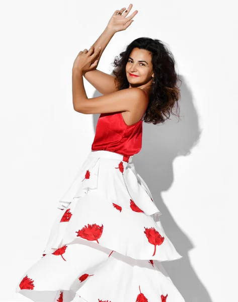 Wunderschöne lächelnde hispanische Tänzerin in rot-weißem Kleid mit Blumenmuster tanzt Carmen Flamenco und hält die Hände in die Höhe — Stockfoto