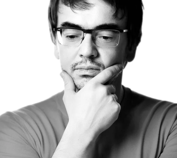 Ritratto in bianco e nero dell'uomo con gli occhiali che tocca il mento e riflette sullo sfondo bianco, primo piano. Esprimere — Foto Stock